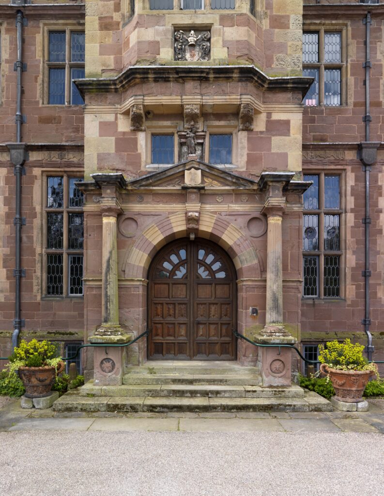 A grand front entrance to a huge hall, with big brown double doors.