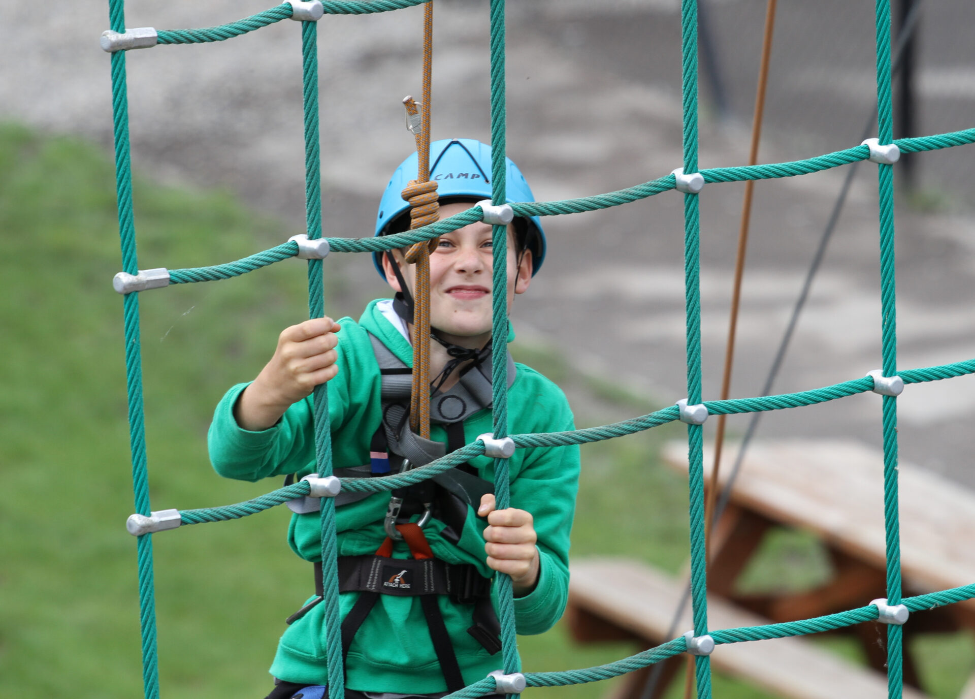 Young boy climbing up a net with a helmet on