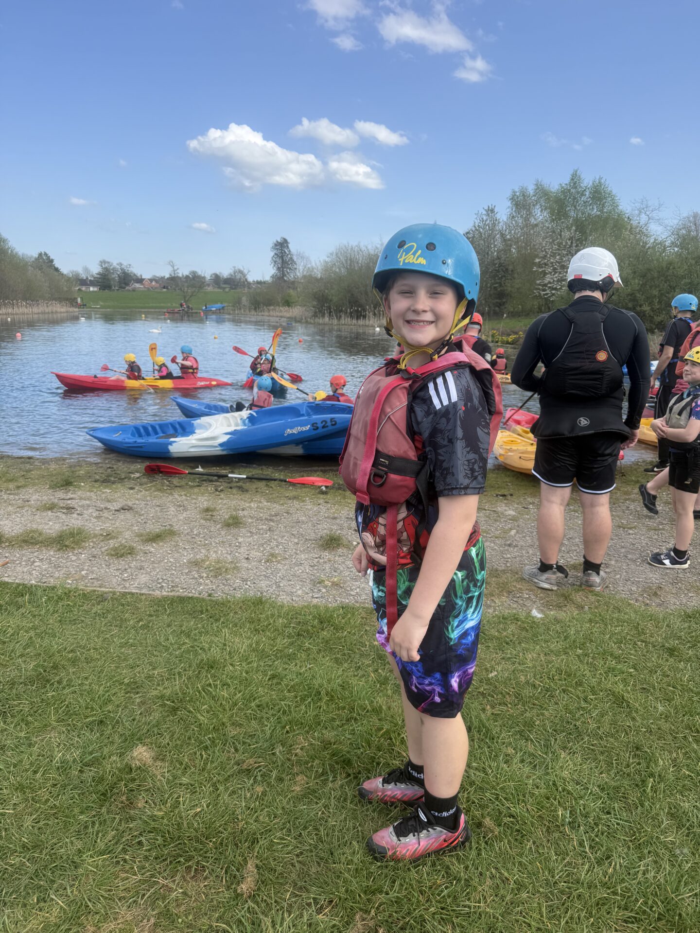 Young boy in front of lake, with kayaks.