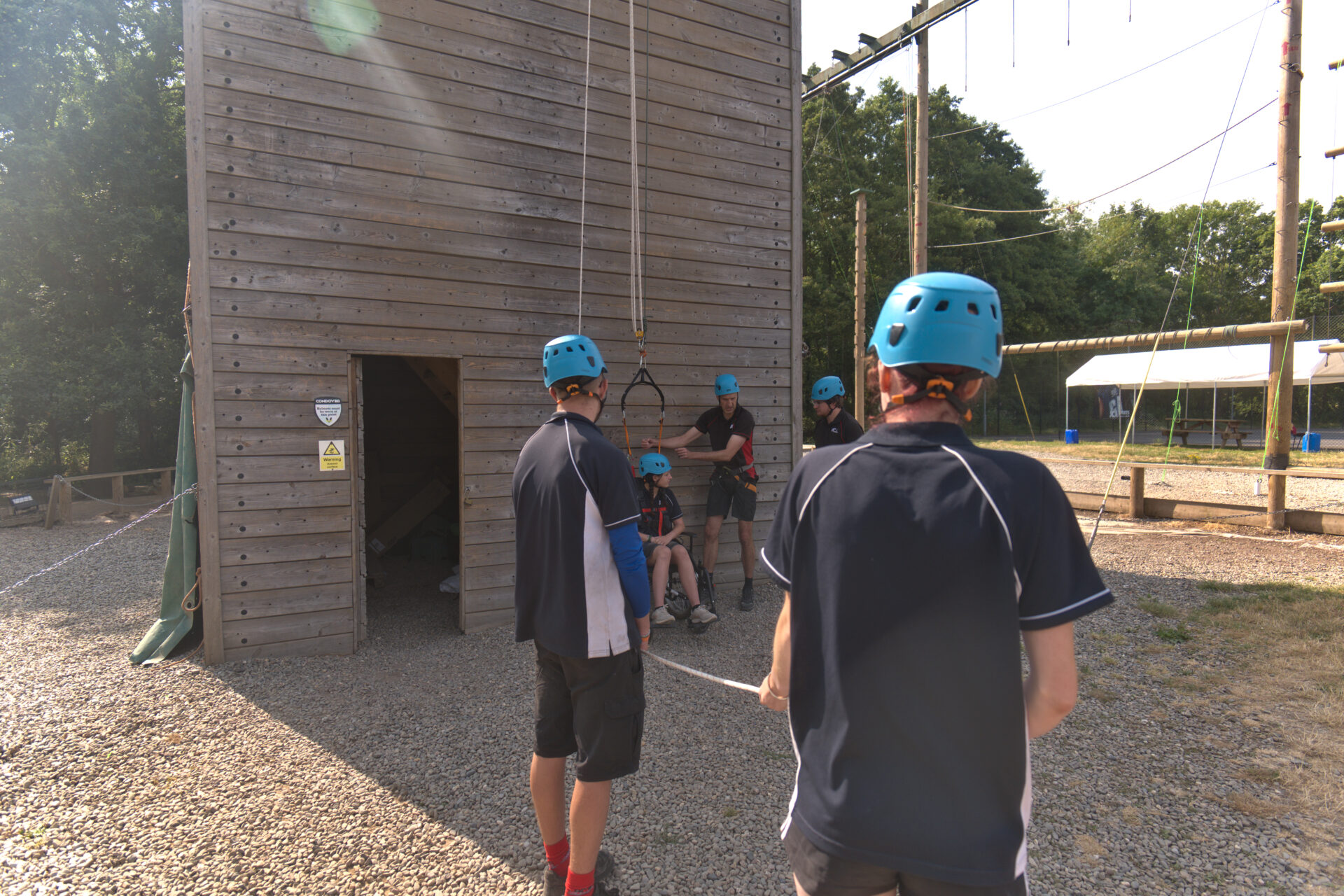 Group of staff working the ropes while a participant is prepared for the adapted climb