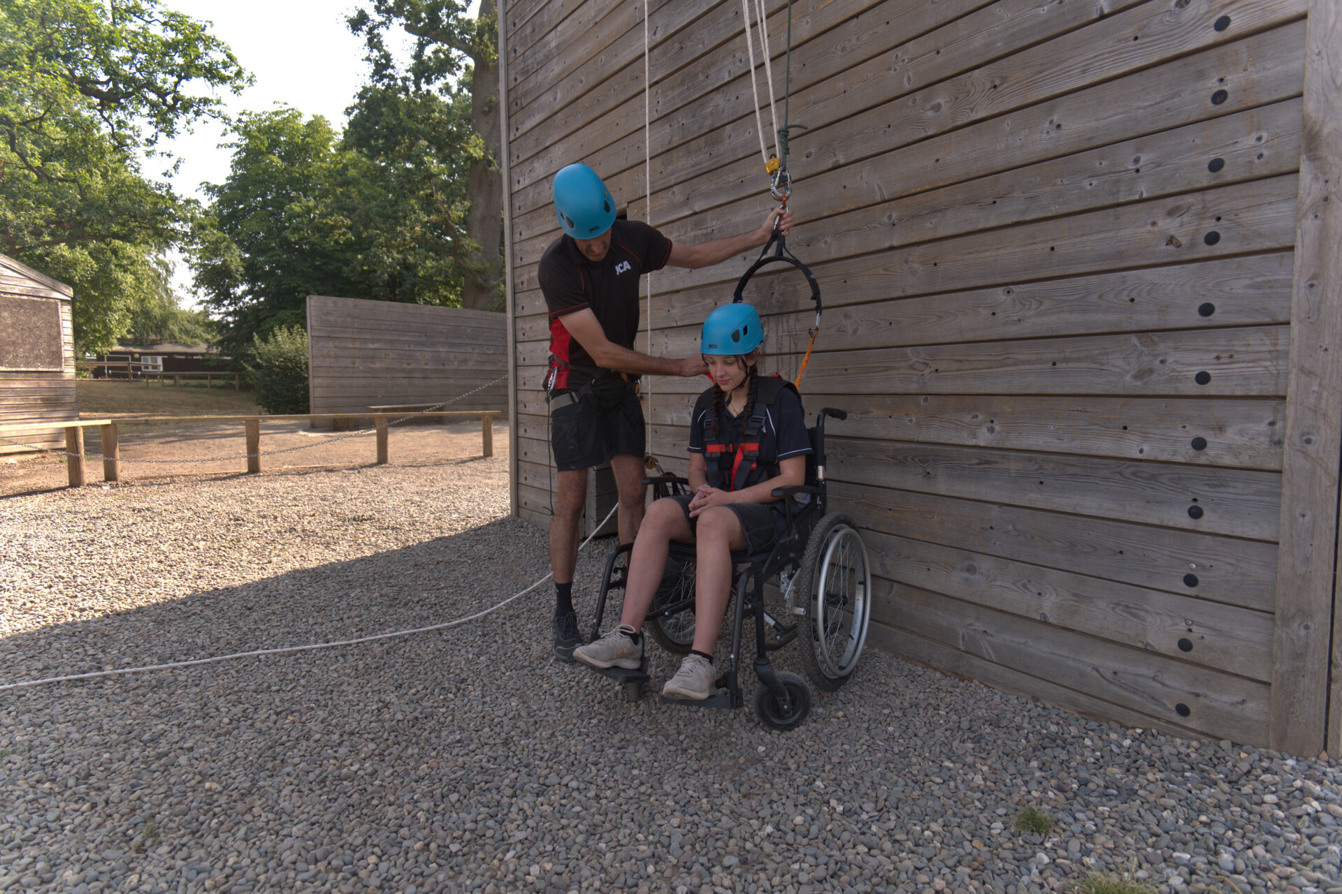 Instructor preparing a young wheelchair user for an adapted climb at the tower