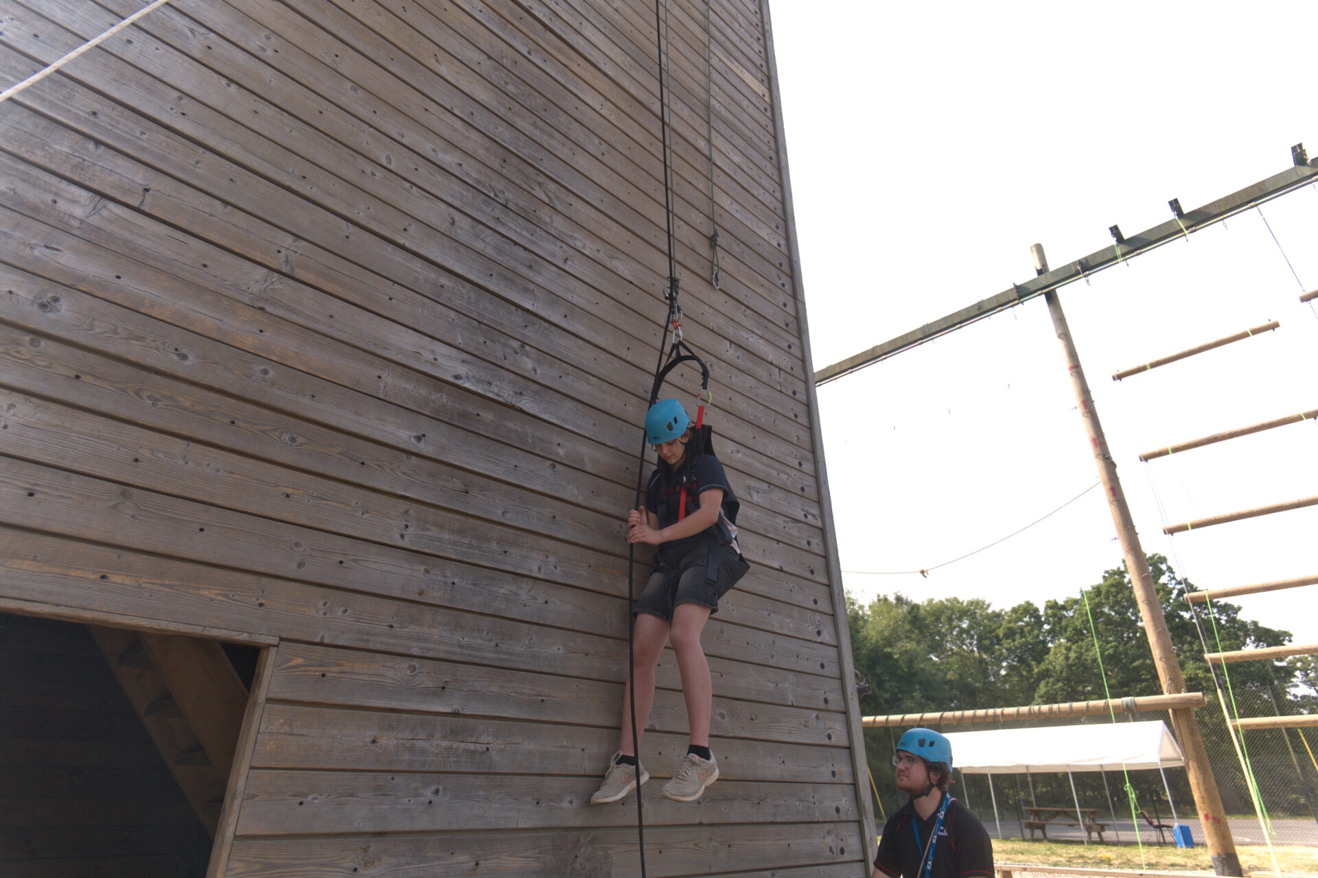Participant being lowered down the climbing tower in an adapted seat