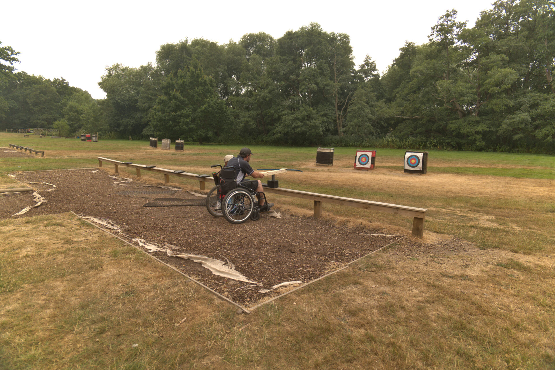 Wheelchair user taking aim from an accessible archery shooting area