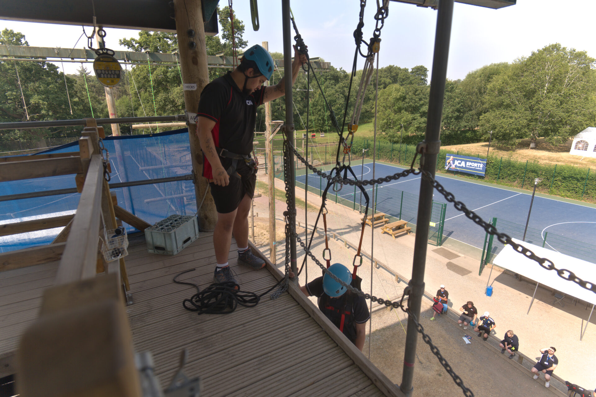 Instructor on the tower platform assisting a participant in an adapted seat