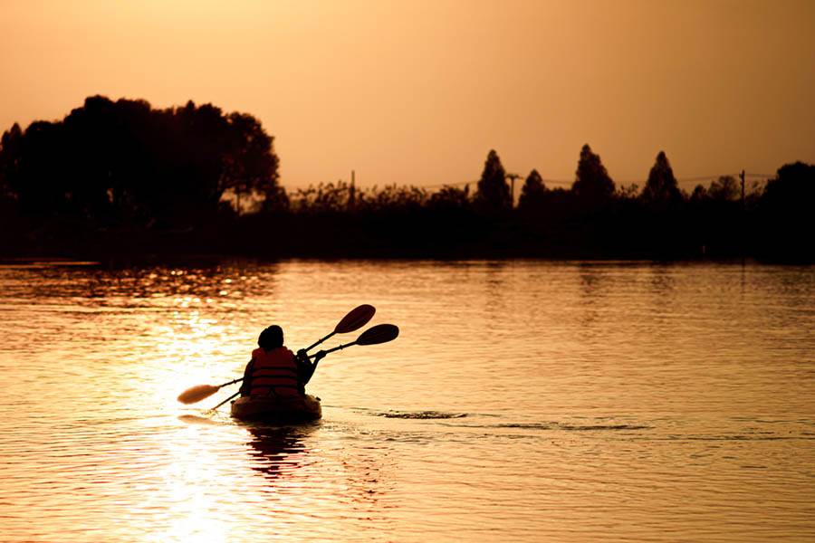 Silhouettes of two kayakers on a lake at sunset